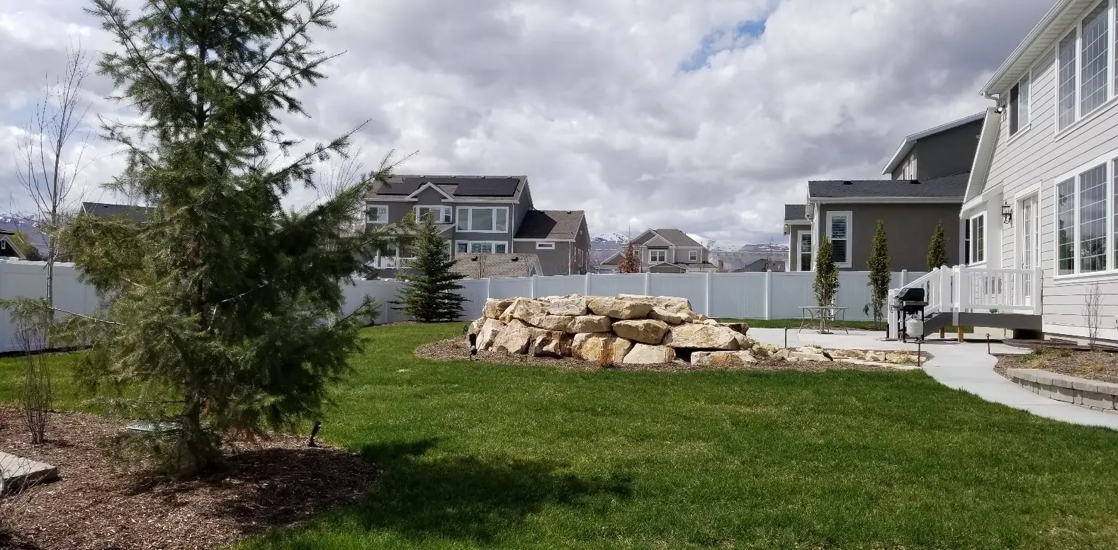 A backyard landscaped with a white vinyl fence